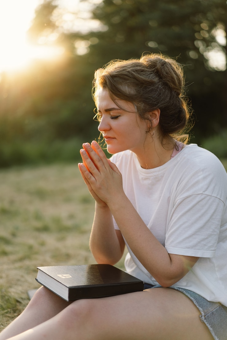 Foto vrouw sloot haar ogen biddend in een veld tijdens prachtige zonsondergang handen gevouwen in gebedsconcept voor ...
