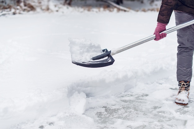 Vrouw sneeuw verwijderen met een schop in de winter. IJsbaan schoonmaken