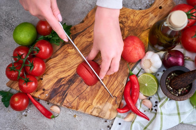 Vrouw snijden en hakken geblancheerde tomaat met mes op houten bord