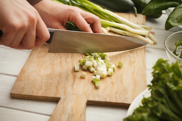 Vrouw snijden lente-ui op een houten bord voor salade. Biologisch voedsel bereiden, natuurlijk zelfgemaakt eten, ruimte kopiëren