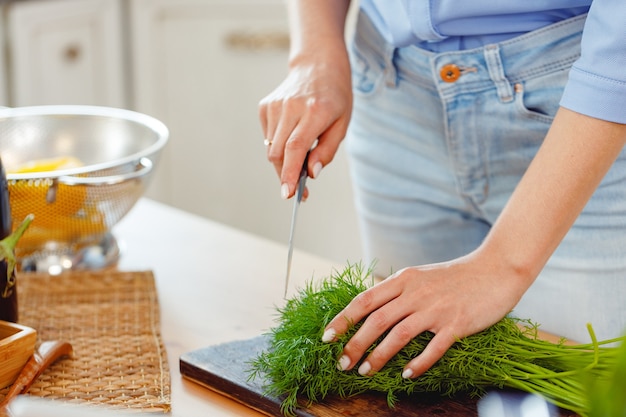 Vrouw snijden peterselie op een houten bord in de keuken