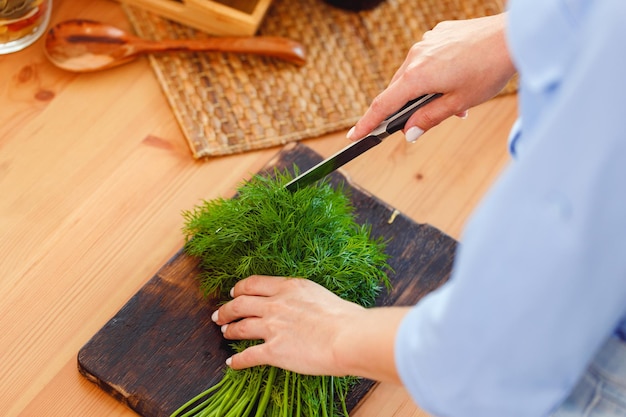 Vrouw snijden peterselie op een houten bord in de keuken