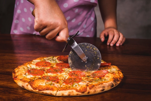 Vrouw snijden pizza met pizzasnijder