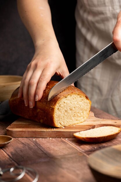 Vrouw snijden zuurdesem wit brood brood op houten bord Zelfgemaakt gezond koken concept