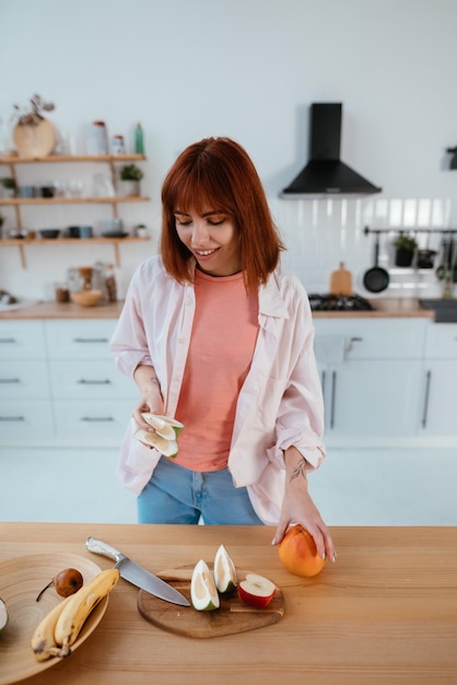 Vrouw snijdt fruit op een bord tijdens het ontbijt