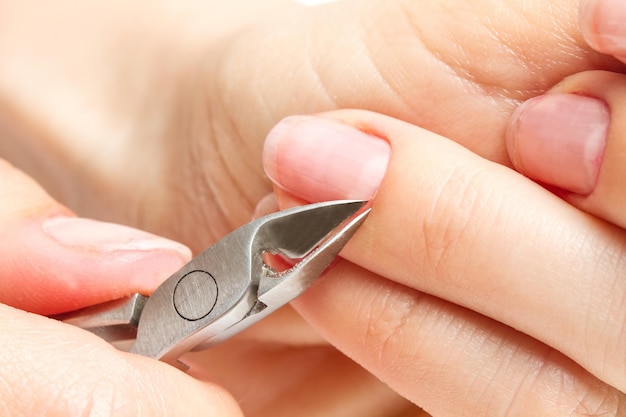 Foto vrouw snijdt haar eigen nagelriem in close-up