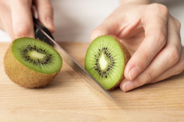 Vrouw snijdt rijpe kiwi's, close-up