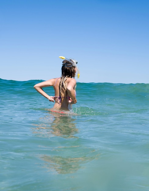 Vrouw snorkelt in de zee tegen een heldere blauwe lucht