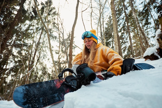 Vrouw snowboarder in helder pak in een sportbril houdt een snowboard vast. Extreme sporten. Vrije tijd.