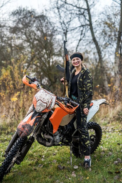 Vrouw soldaat poseren met geweer en motorfiets