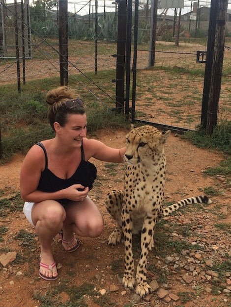 Vrouw speelt met luipaard in de dierentuin tegen de lucht