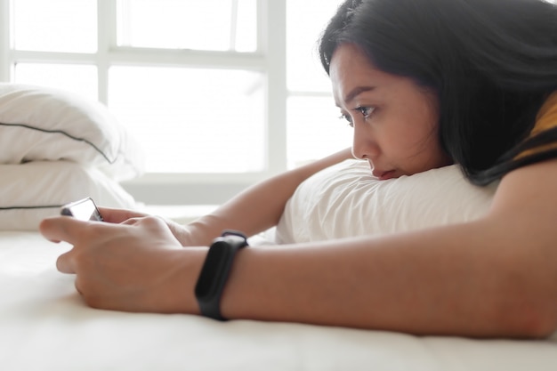 Vrouw speelt mobiel spel in haar slaapkamer