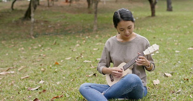 Foto vrouw speelt ukulele in het park.