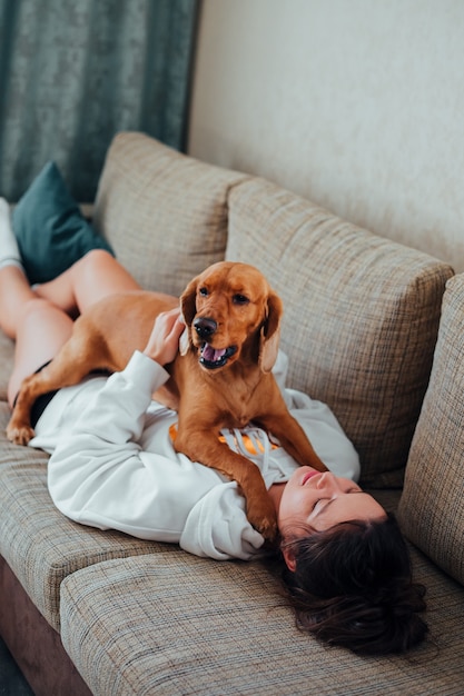 Vrouw spelen met hond op de bank liggen