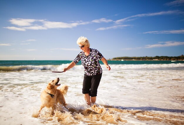 Vrouw spelen op het strand met golden retriever