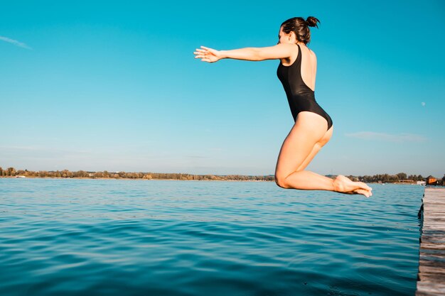 Vrouw springt van houten pier in meerwater