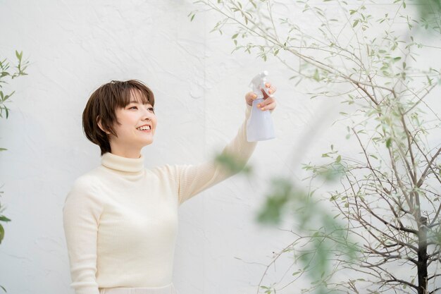 Vrouw sproeien van water op planten in de tuin van het huis