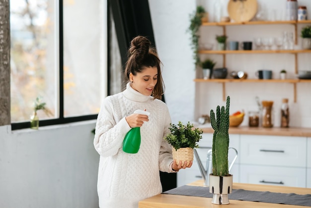 Vrouw sproeit water op kamerplanten in bloempotten door sproeier