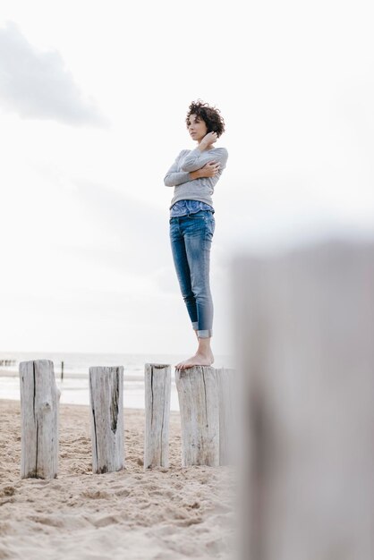 Foto vrouw staande op houten staak op het strand