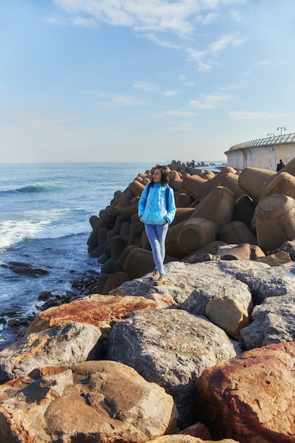 Vrouw staat aan de kust van de Atlantische Oceaan, woeste golven die de kust raken, de branding