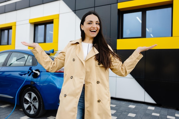 Vrouw staat bij de auto en laadt elektrische auto op bij het laadstation