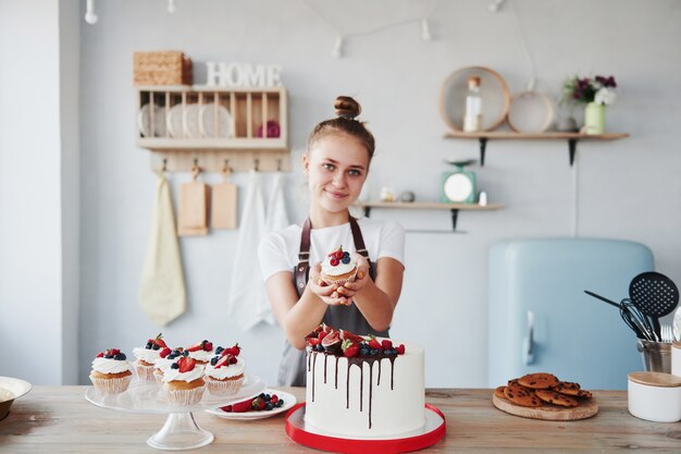 Vrouw staat binnen in de keuken met zelfgemaakte taart.