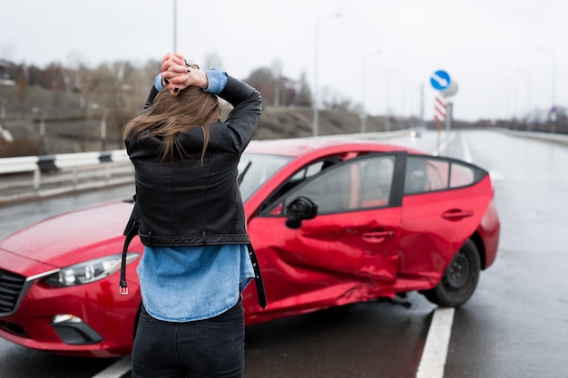 Vrouw staat in de buurt van een kapotte auto na een ongeval. roep om hulp. autoverzekering