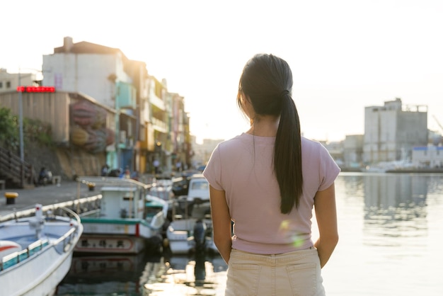 Vrouw staat naast de pier onder de zonsondergang