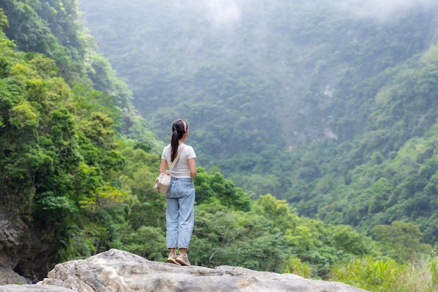 Vrouw staat op de rots en kijkt naar het bos uitzicht