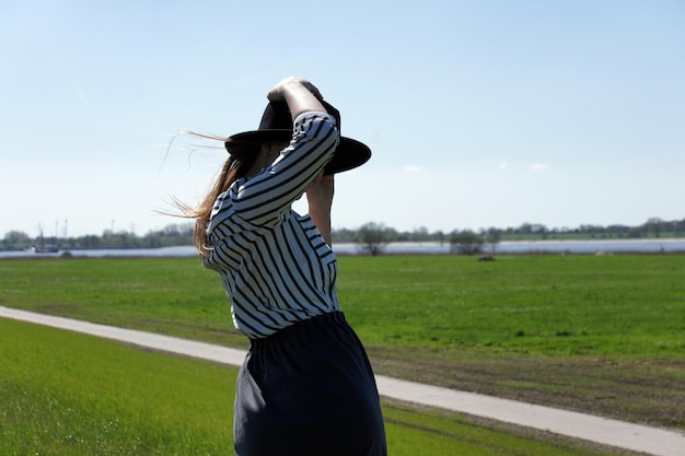 Foto vrouw staat op het veld tegen de hemel.