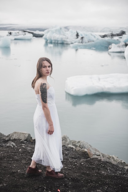 Vrouw staat tegen de achtergrond van gletsjers in IJsland