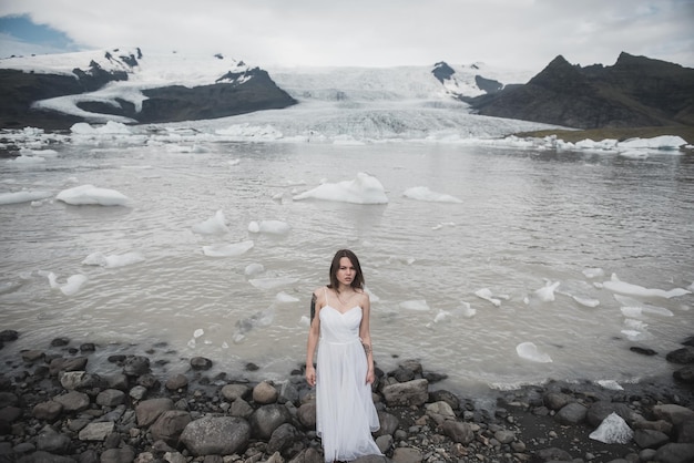 Vrouw staat tegen de achtergrond van gletsjers in IJsland
