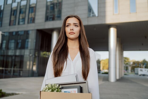 Vrouw staat voor glazen modern gebouw van corporatiekantoor waar ze werkte