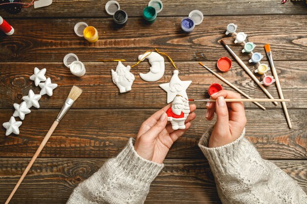 Vrouw stijlvolle kerstcadeaus maken, schildert porseleinen beeldjes