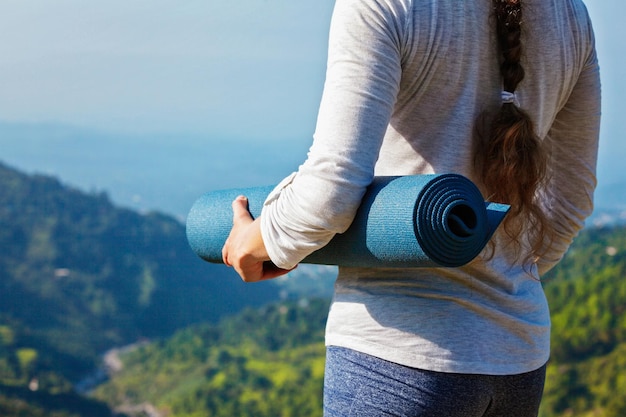 Vrouw stond met yogamat buiten in de bergen en maakte zich klaar voor yoga-oefening