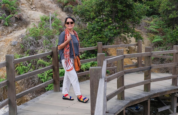 Vrouw stopt bij een houten brug over rotsachtige landen na een lange wandeling op een zonnige dag