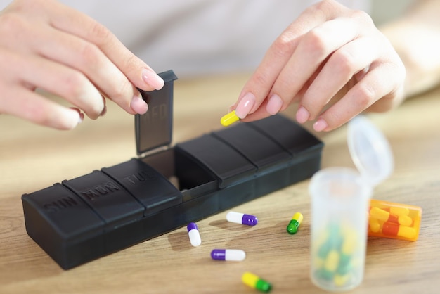 Vrouw stopt medische pillen voor de behandeling van ziekten in een doos met secties voor de voorbereiding van de dosis
