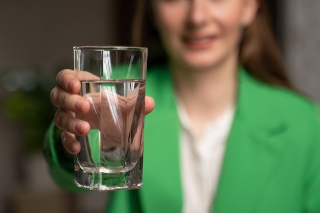 Vrouw strekt hand uit met glas met water om te drinken