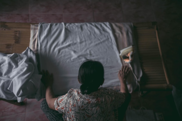 Foto vrouw strijkt laken op bed.