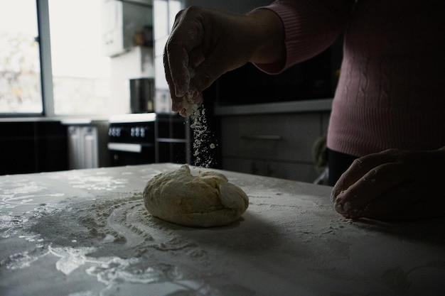 Foto vrouw strooit meel op het deeg