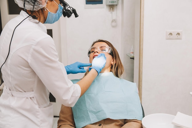 Vrouw tandarts behandelt tanden van een jonge vrouw die in de kliniek ligt. arts behandelt tanden.