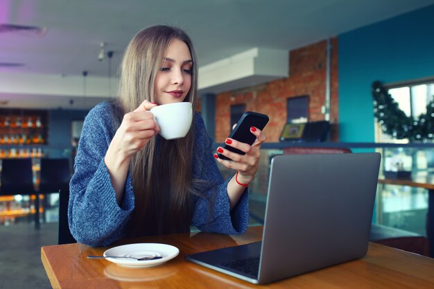 Vrouw tekstbericht typen op slimme telefoon in een café.