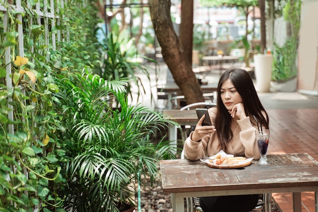 Vrouw texting op mobiele telefoon in café