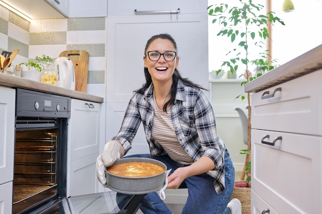 Vrouw thuis in de keuken die hete appeltaart uit de oven haalt