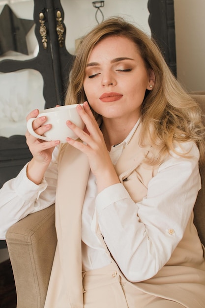 Vrouw thuis met kopje koffie op de bank met gesloten ogen
