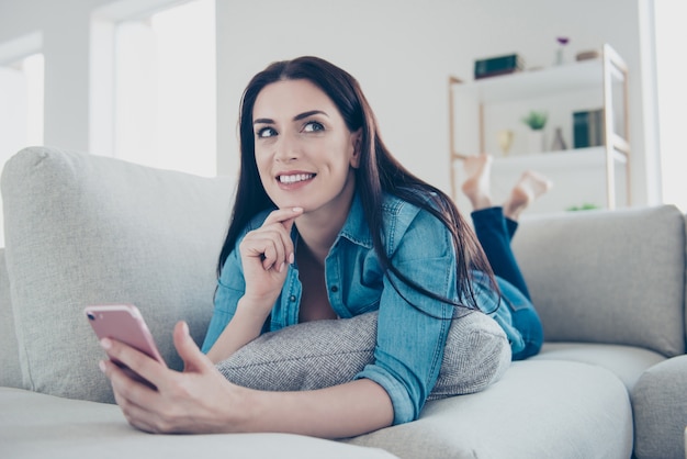 Vrouw thuis op de bank met behulp van smartphone