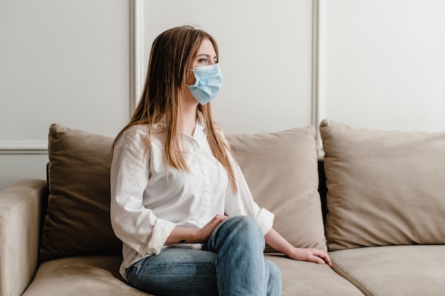 Vrouw thuis op de bank met masker