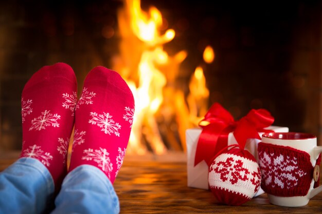 Vrouw thuis. Voeten in kerstsokken bij open haard. Ontspannend en comfortabel. Winter vakantie concept