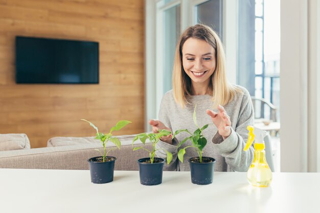 vrouw thuis zorgt voor bloempotten schenkt bloemen zittend aan tafel