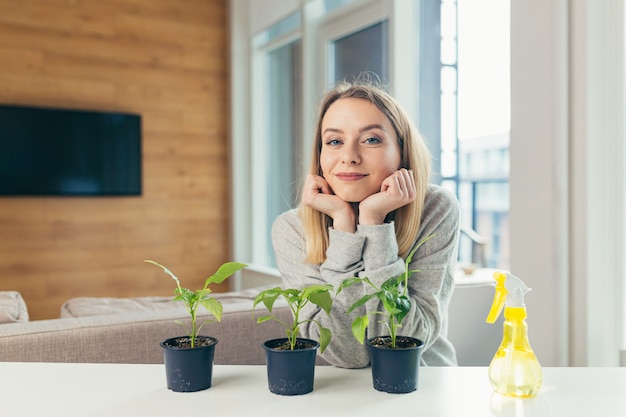 Vrouw thuis zorgt voor bloempotten schenkt bloemen zittend aan tafel